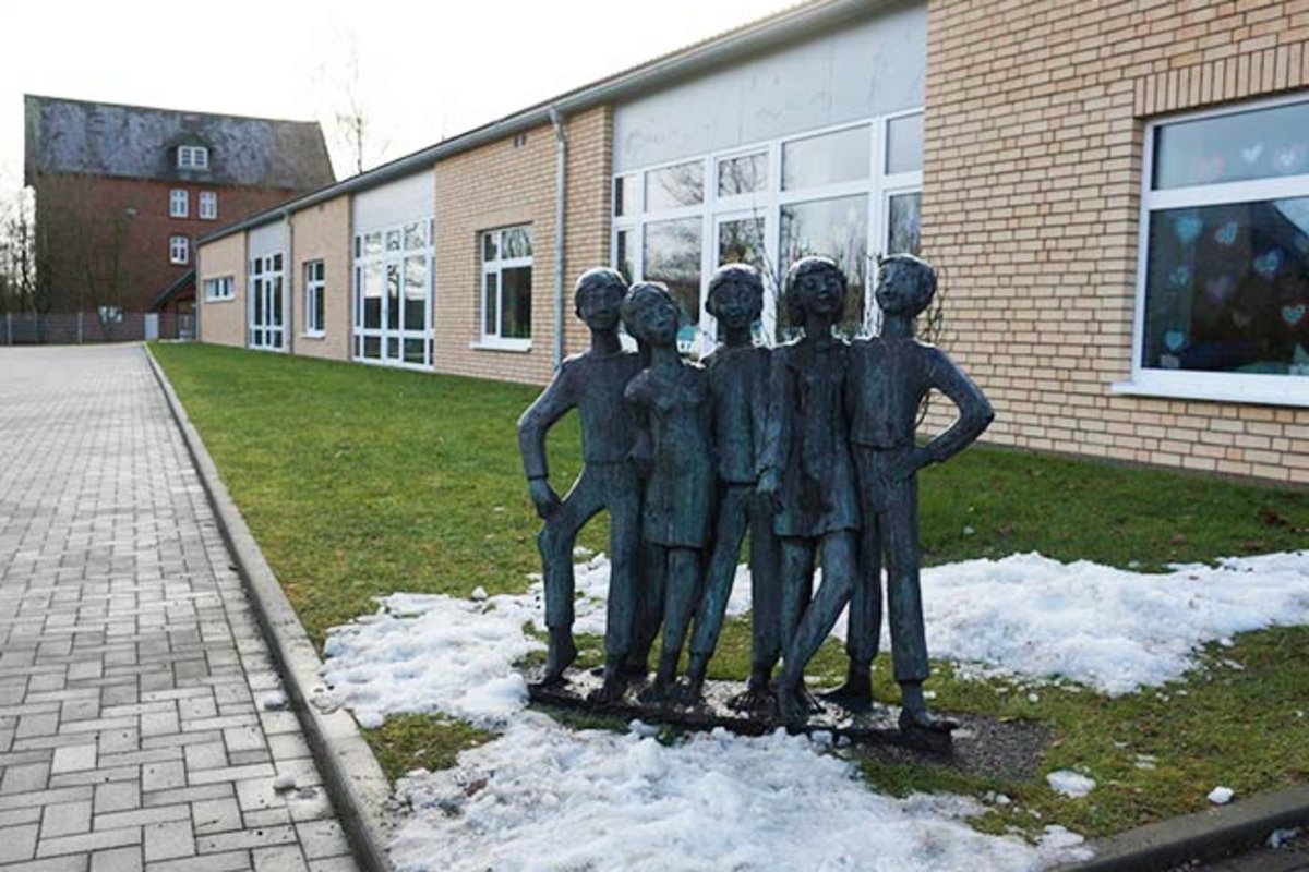 Gebäude der Grundschule Hennstedt mit Statue davor