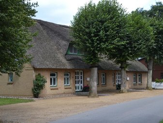 Reetdachhaus mit grünen Fensterrahmen